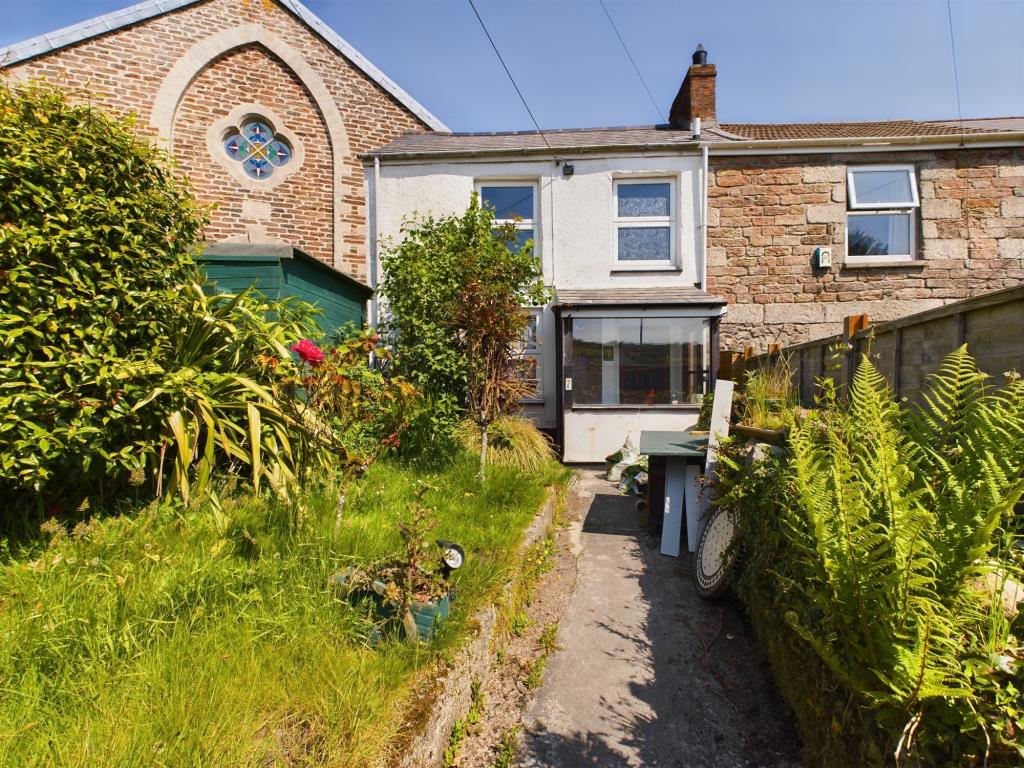 Lot: 62 - END-TERRACE COTTAGE FOR IMPROVEMENT IN VILLAGE LOCATION - Front elevation of cottage with garden area